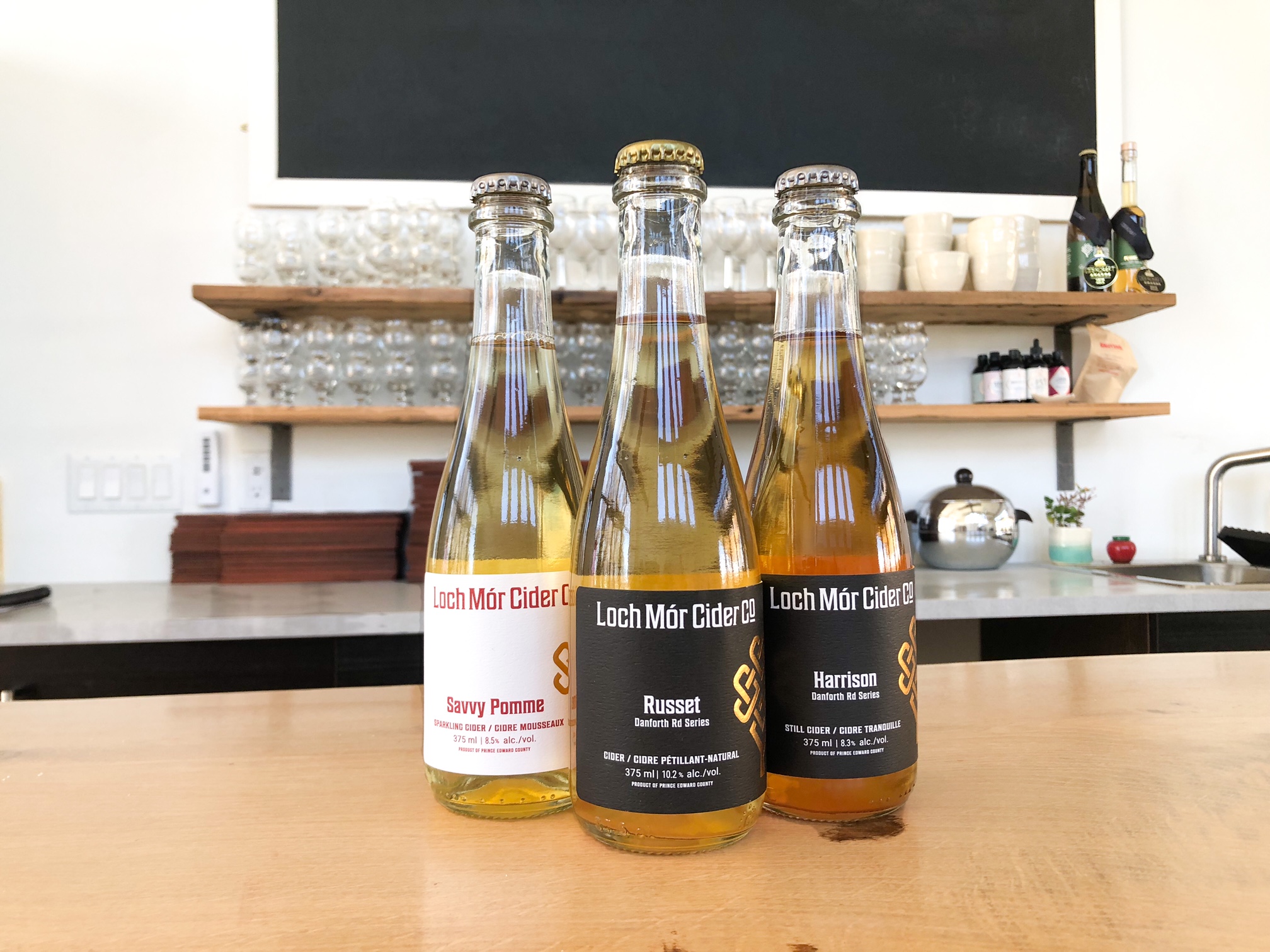Trio of Loch Mor 375ml cider bottles Trio 375ml bottles Russet, Harrison, Savvy Pomme dry craft ciders on tasting room bar top prince edward county
